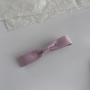 Barrette élégante en satin violet lavande sur un fond texturé en cuir blanc