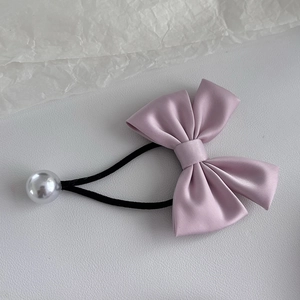 Détail du chouchou nœud en satin rose doux avec une breloque en perle blanche
