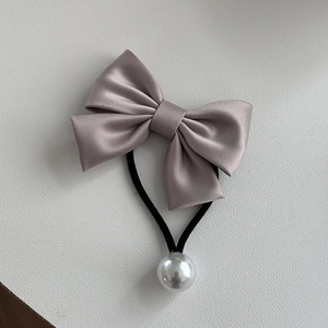 Détail d'un chouchou élégant avec nœud en satin et perle sur fond minimaliste