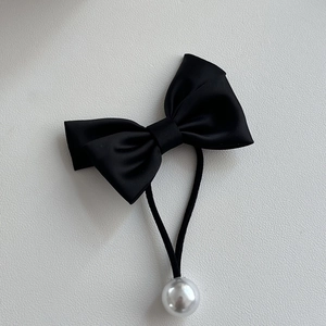 Détail de chouchou noeud en satin noir avec bande élastique et perle blanche décorative