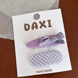 Détail du nœud en tissu violet et des barrettes à carreaux sur carte de support