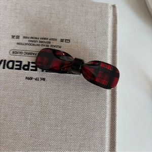 Elegante fermaglio per capelli a fiocco in acetato a quadri rossi e neri su sfondo neutro