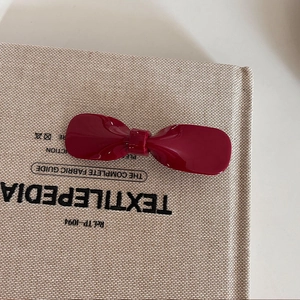 Elegante fermaglio per capelli a fiocco rosso scuro su un libro per un look retrò raffinato