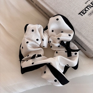 Detailed macro of white polka dot scrunchie with black lace trim and bow on textile book