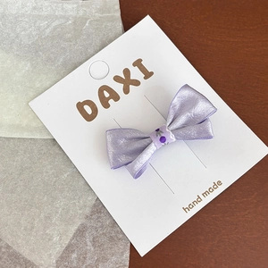 Pince à cheveux noeud en satin violet avec ruban floral et perle sur carte blanche