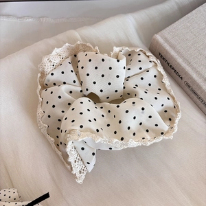 Macro view of cream chiffon polka dot scrunchie with lace edge on fabric