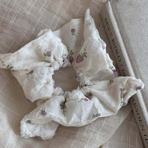 Detail of floral chiffon scrunchie with purple rose patterns on beige linen background