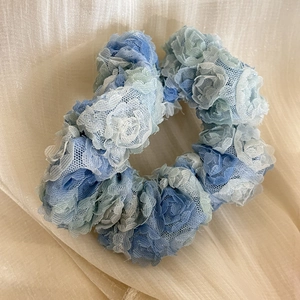Dettaglio dell'elastico per capelli con fiori in pizzo blu e trama in mesh