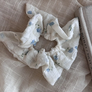 Close-up of a floral hair scrunchie with blue patterns on ivory translucent tulle fabric