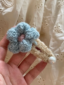 Detalle de pinza para el pelo con flor azul claro tejida a mano y perla sobre encaje