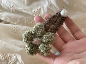 Vista detallada de una pinza para el pelo de flor de ganchillo verde con perla blanca