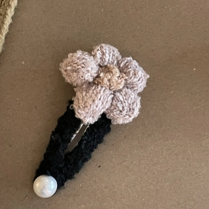 Detalle de una pinza para el cabello con flor de ganchillo hecha a mano y una perla blanca