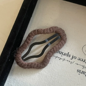 Detail view of wavy brown plush hair clip texture and coffee color fabric material