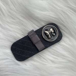 Detail of a dark grey plaid fabric hair clip with a vintage gold bow button accent