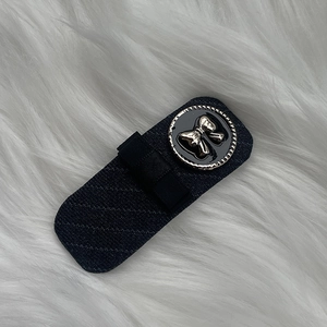 Detailed view of navy blue fabric hair clip featuring a golden bow relief button detail