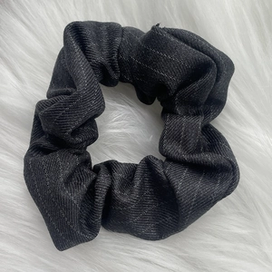 Close-up of a charcoal grey pleated fabric scrunchie with subtle silver glitter on plush background
