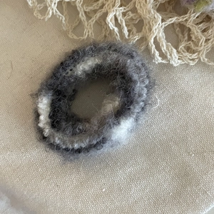 Fluffy grey and white mohair scrunchie with high elasticity on beige canvas background