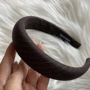 Close-up of handmade wide brown headband with gold silk texture and internal label