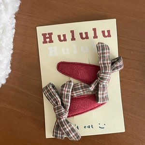 Pair of corduroy plaid bow hair clips for girls on display card over wooden desk