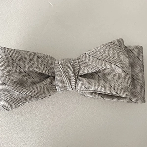 Close-up of a grey herringbone fabric bow hair clip with elegant woven texture