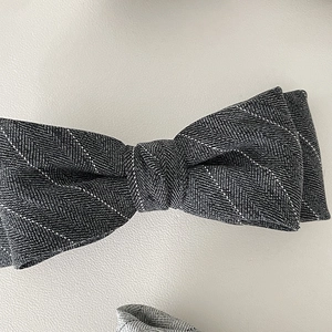 Grey herringbone bow hair clip with white polka dots pattern and spring fastener