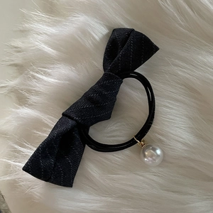 Elegant black bow hair tie with a white pearl pendant on a soft white fur background