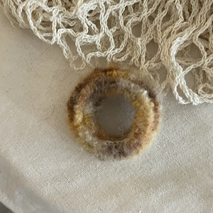 Close-up of soft mohair crochet hair tie with gradient earth tones on textured fabric