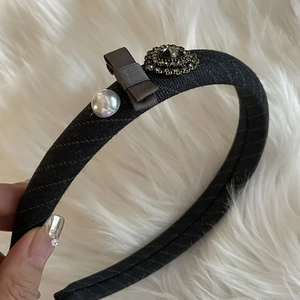 Detail of vintage headband with brown satin bow, faux pearl and rhinestone floral ornament