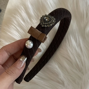 Detail of vintage brown plaid headband featuring rhinestone flower, bow, and pearl decoration