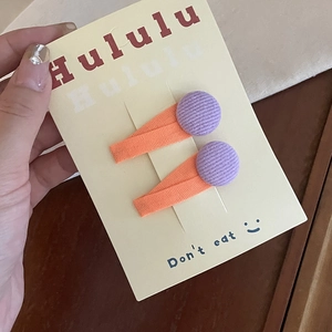 Close-up of handmade fabric hair clips in orange and purple tones for little girls