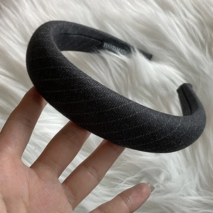 Detail of a handmade black padded headband showing textured fabric and a handmade label