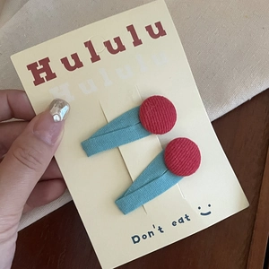 Close-up of colorful fabric hair clips with red cloth buttons on a brand display card