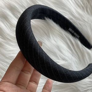 Detail showing the thick black sponge headband with a Hand Made woven label and fabric texture