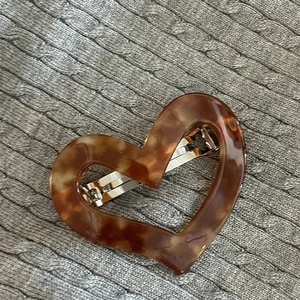 Brown tortoiseshell heart hair clip with metal spring clasp on knitted background