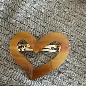 Detailed close-up of heart-shaped amber resin hair clip with silver metal spring buckle