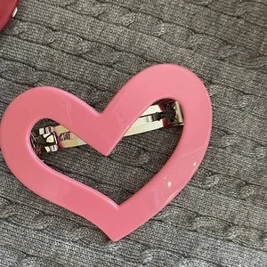 Macro shot of a glossy pink heart-shaped hair clip with a silver metal spring back