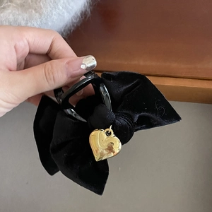 Close-up of velvet bow hair claw with a gold heart pendant and elegant black texture