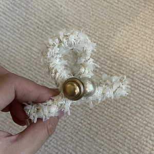 Pince à cheveux élégante en tweed blanc avec perle dorée et accent nacré, vue à la main