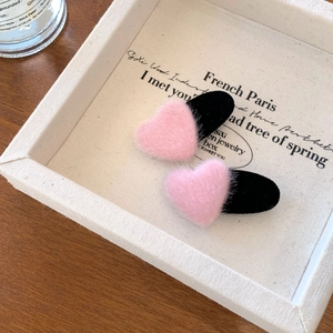 Pink faux fur and black velvet heart hair clips displayed on a rustic wooden tray
