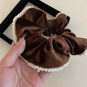 Detailed texture of brown velvet hair scrunchie with white pearl trim embellishment