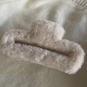 Detailed view of the soft beige plush hair claw clip featuring a cozy winter faux fur texture