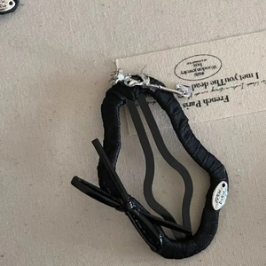 Macro shot of black ribbon hair tie with silver rose metal charm and handmade tag