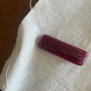 Macro detail of dark purple rectangular hair clip featuring golden French script lettering