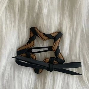 Brown leather star hair clip with black ribbon bow on white faux fur background