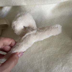 Gros plan d'une pince à cheveux en peluche blanc cassé montrant la texture douce