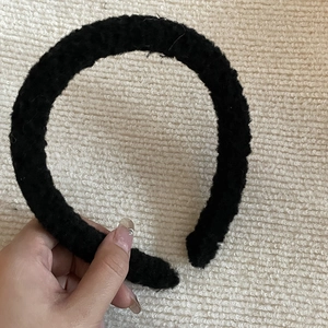 Gros plan d'un serre-tête large en laine d'agneau noire avec une texture douce et chaude