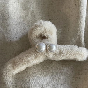 Détail d'une pince à cheveux en peluche crème ornée de perles élégantes sur fausse fourrure