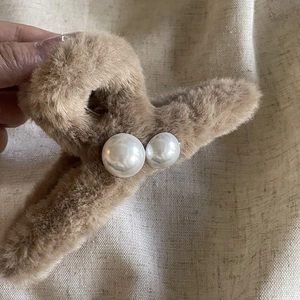 Détail d'une grande pince à cheveux en peluche marron avec deux perles blanches