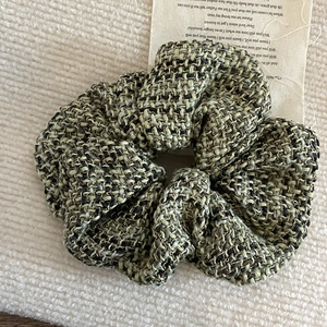 Detail view of large green tweed scrunchie with vintage French weave texture for hair