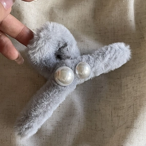 Gros plan sur la pince à cheveux en peluche gris foncé avec perles blanches et fausse fourrure